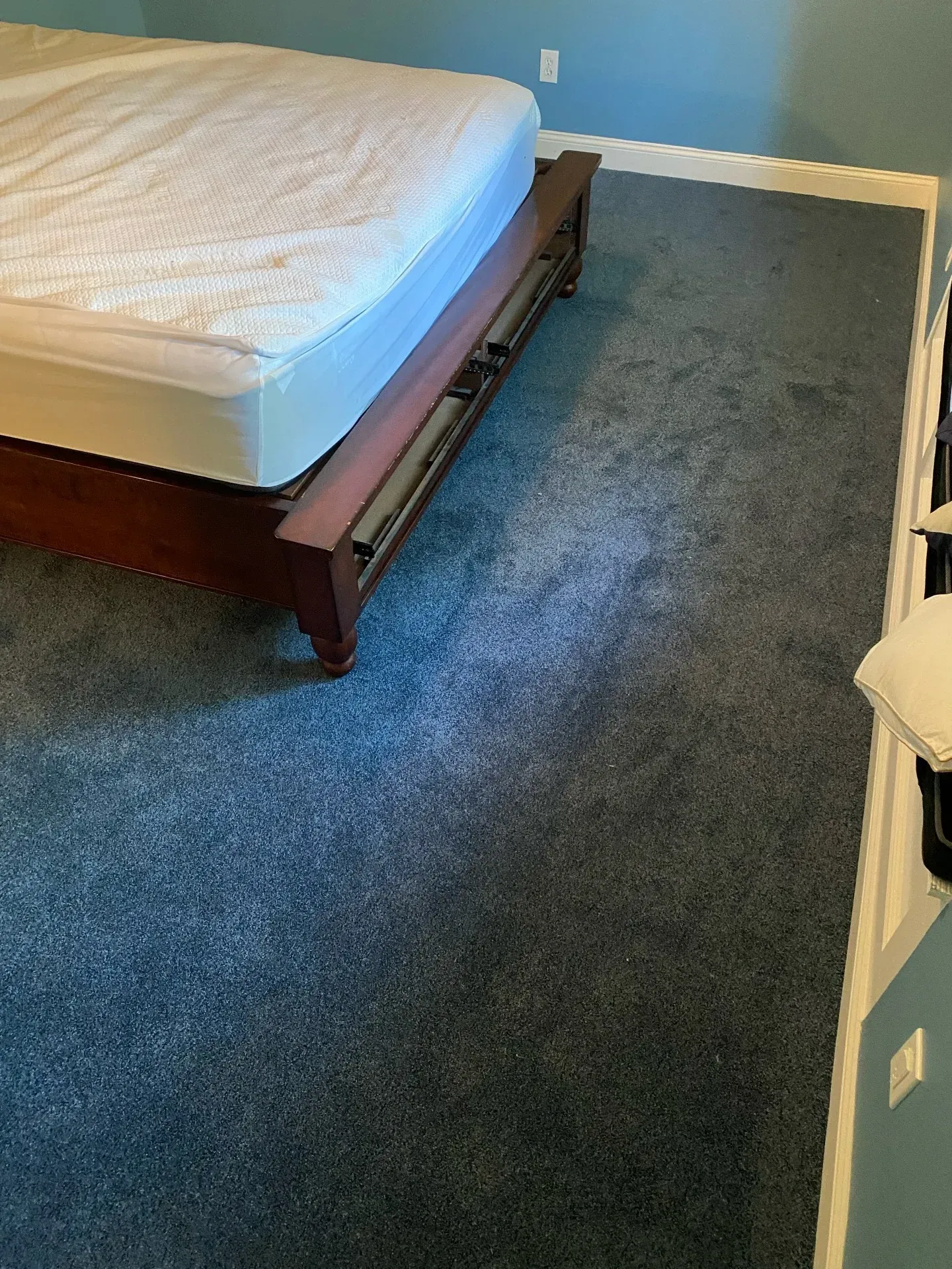Bedroom with bed on wooden frame beside a blue carpeted floor area