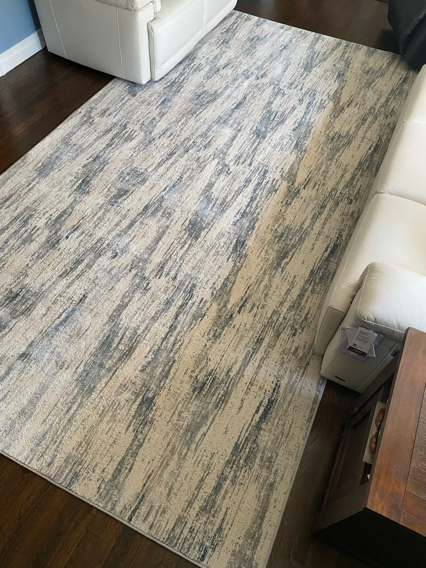 Gray-and-cream patterned runner rug on a dark wood floor beside a white sofa and cabinet.