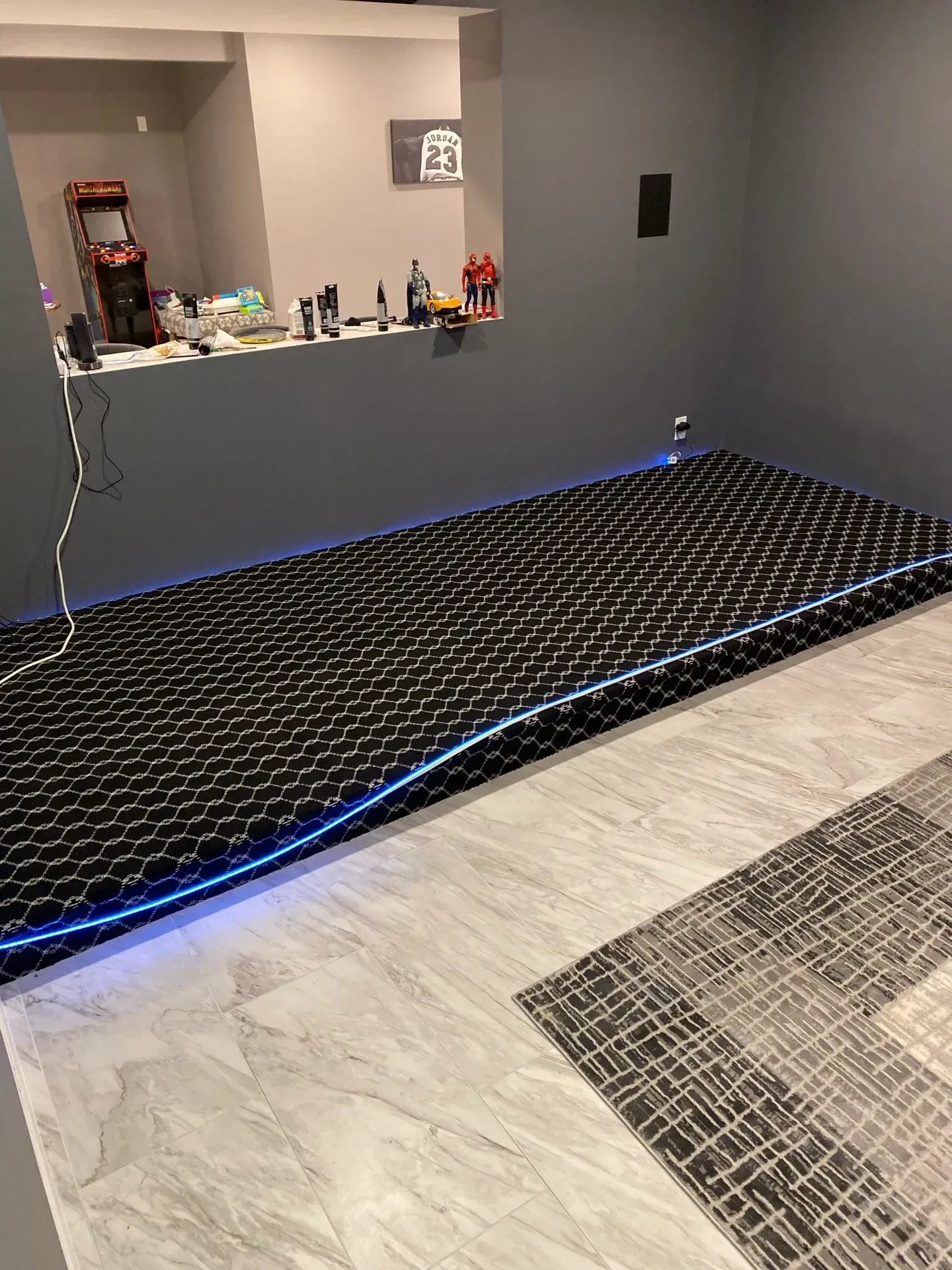 Black textured ramp with blue LED edge in a gray indoor lobby or hallway.