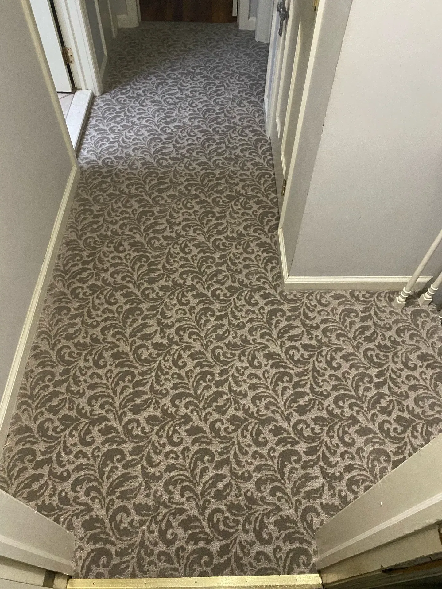 Carpeted hallway with patterned floor and open doorways on both sides