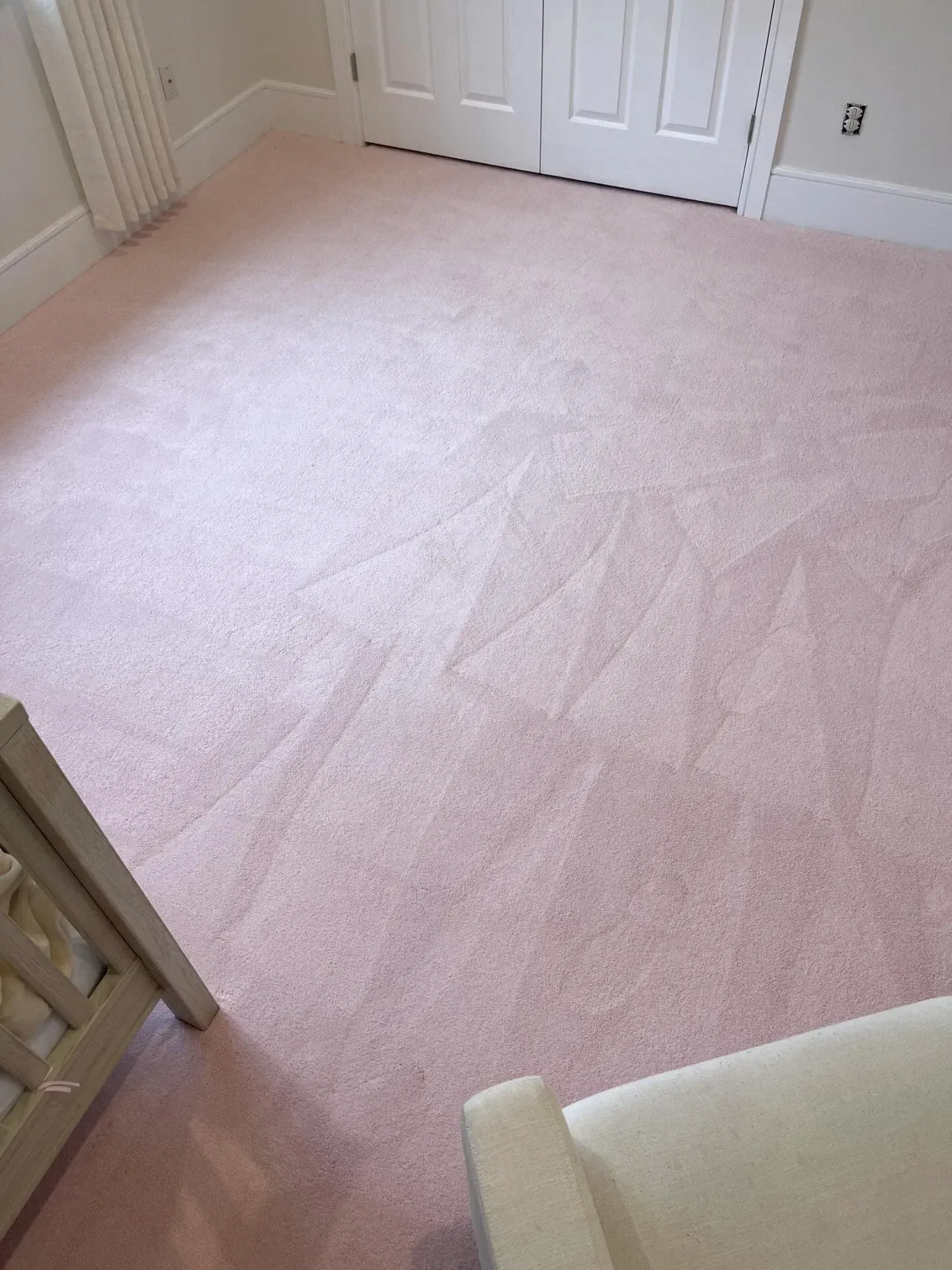 Empty room with light pink carpet and white double doors, viewed from a doorway