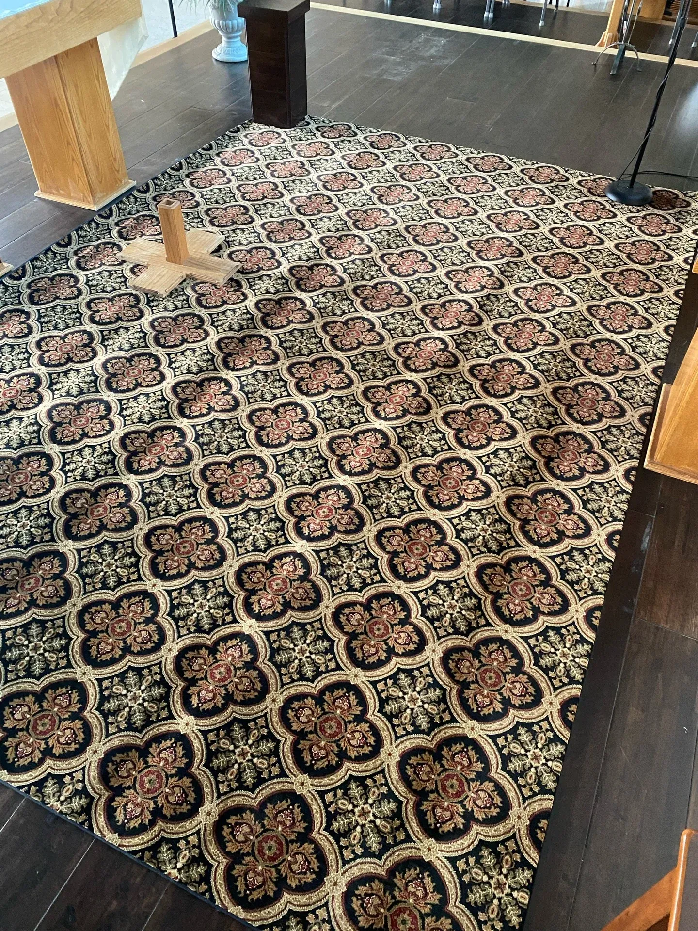 Patterned rug on a wooden floor with a small tan kitten near the top left.