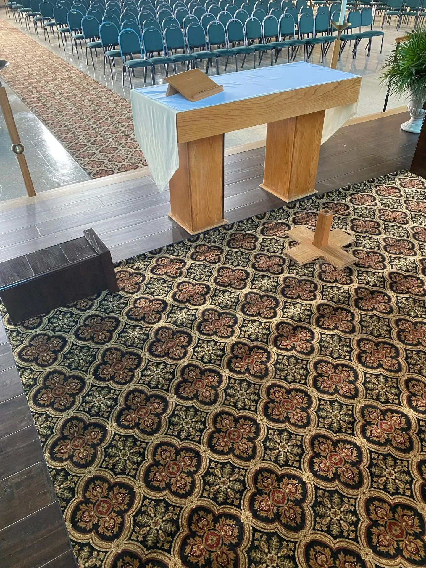 Small altar on patterned rug beside an outdoor pool with rows of blue chairs.