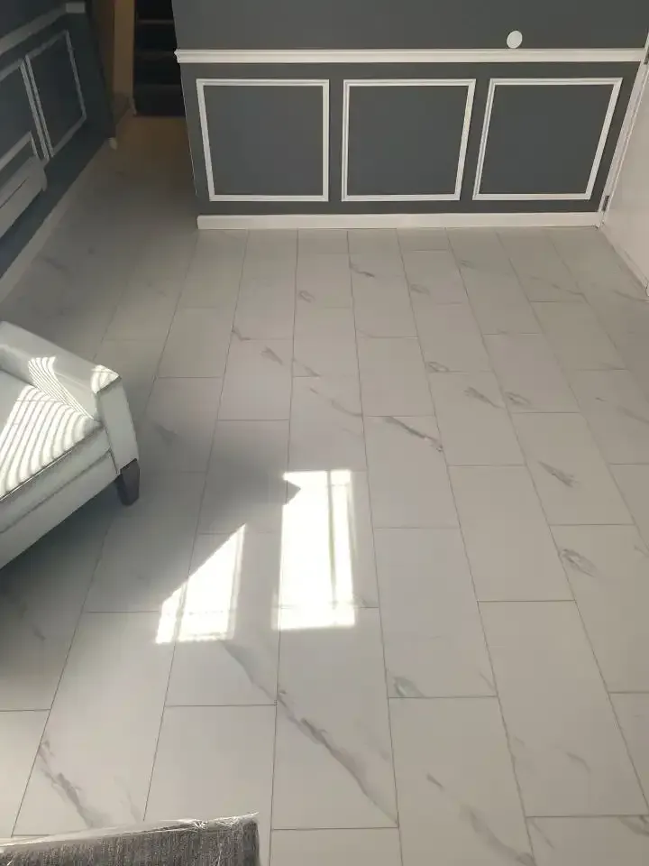 Sunlit tiled living room with gray paneled cabinet and a white chair by the window