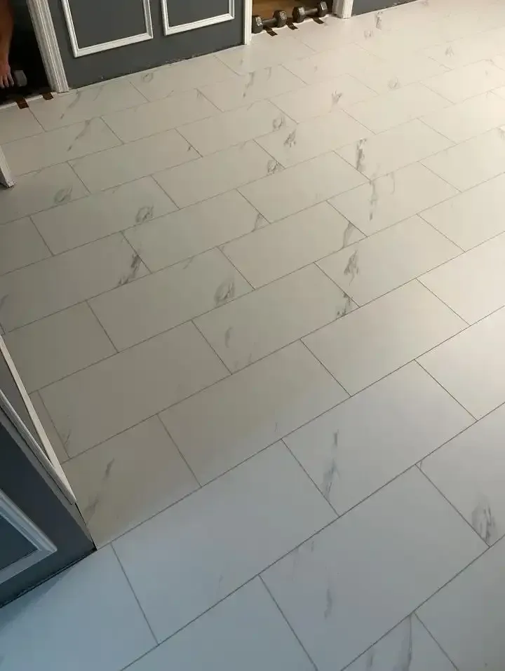 Light gray tiled floor with white marble-like veining in a kitchen or entryway