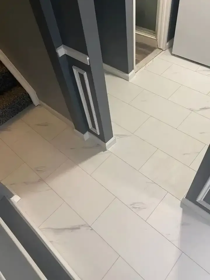 Narrow bathroom hallway with dark doors and light tiled floor, viewed from above