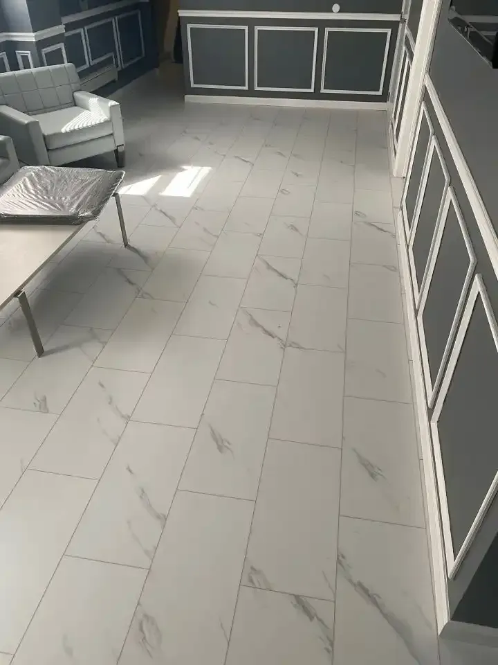 Empty tiled patio with white-framed wall panels and a lounge chair in the corner.