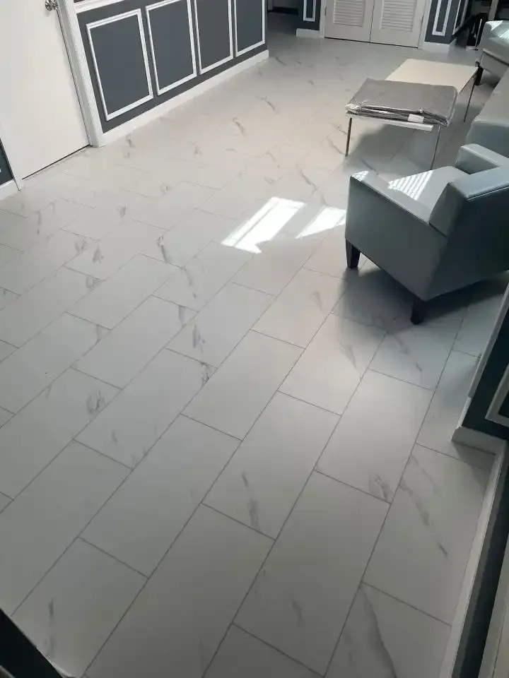 Empty modern room with tiled floor, gray chairs, and sunlight streaming in from a window.