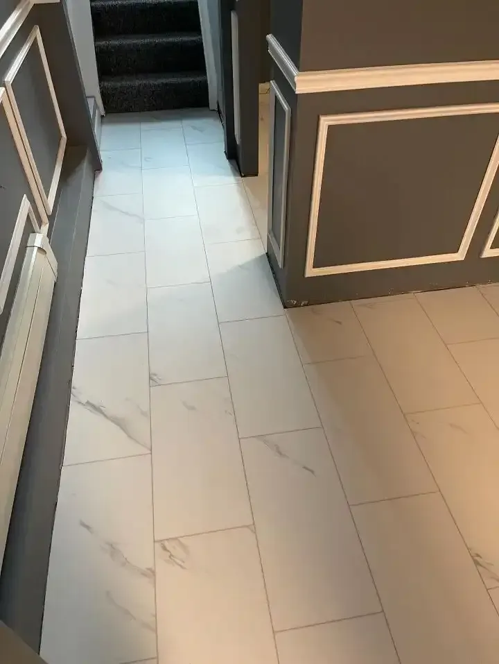 Hallway with cream tile floor and dark paneled walls leading to stairs