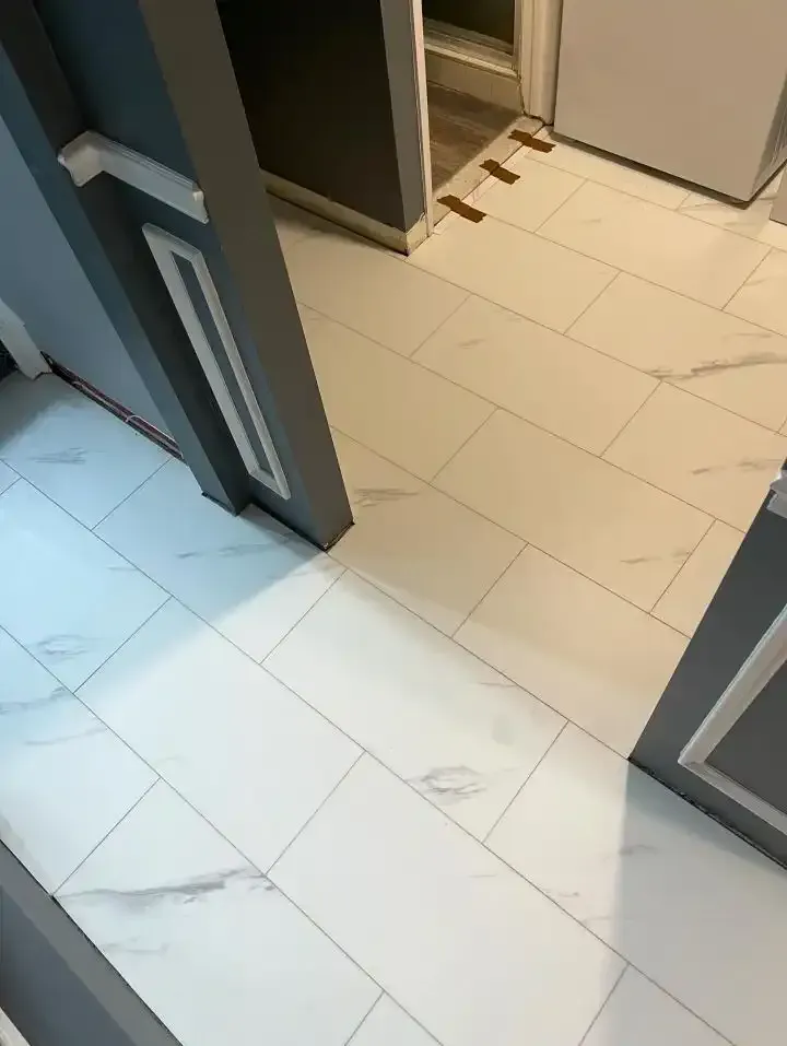 White tiled hallway with open gray doors and a partially visible cabinet or locker area