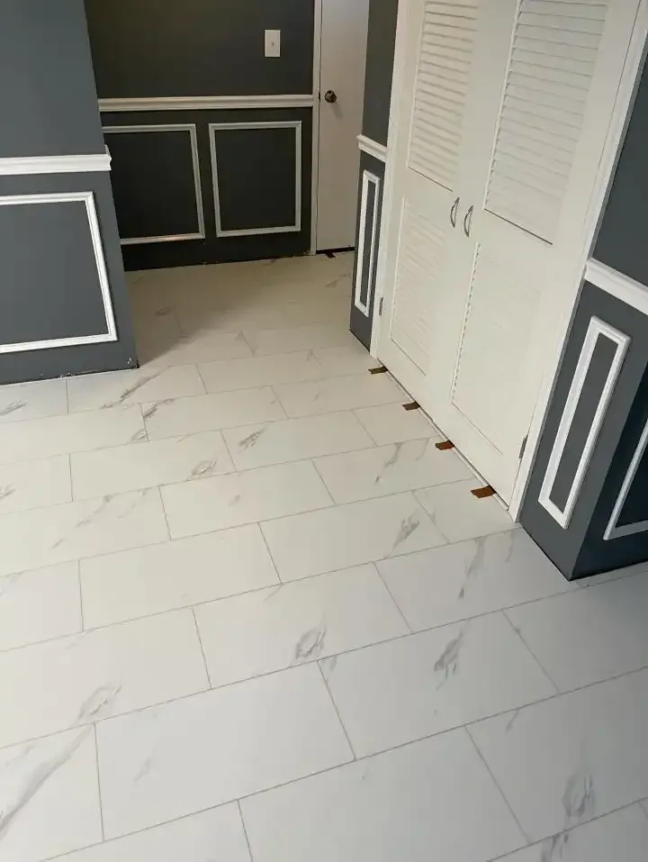 Empty kitchen with white tile floor, dark gray cabinets, and white double closet doors.