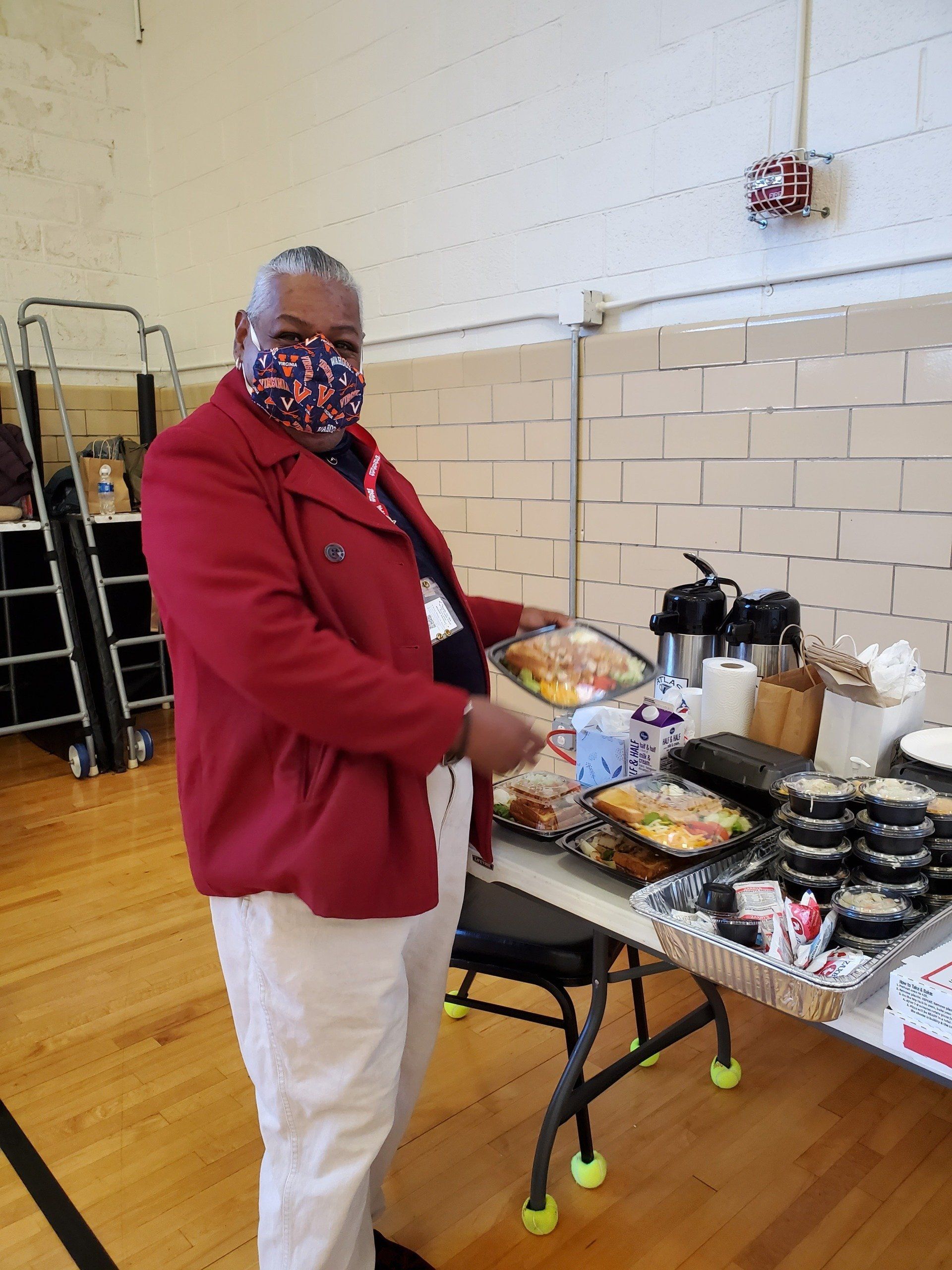 A man wearing a mask is standing in front of a table full of food.