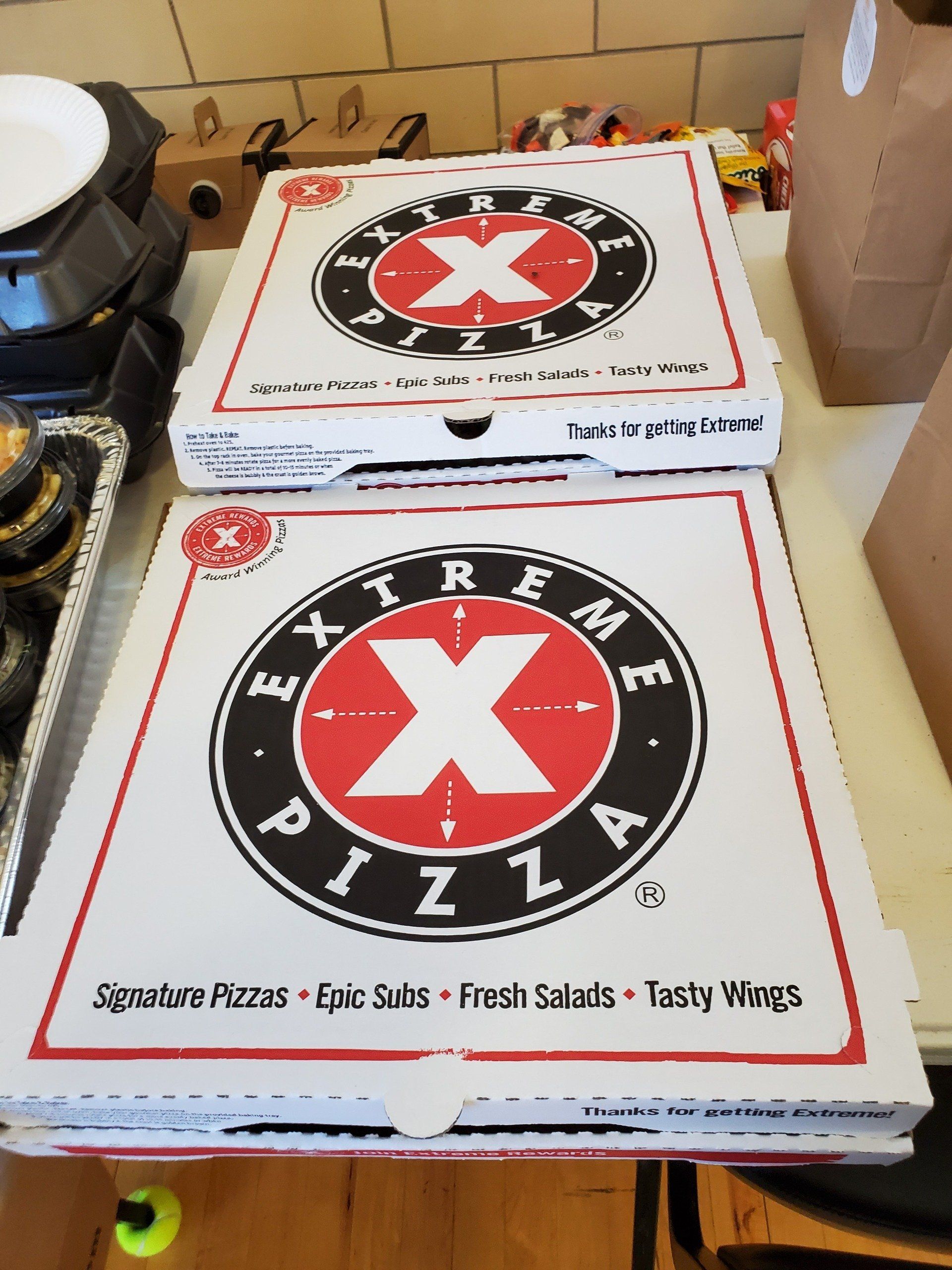 Two boxes of extreme x pizza are stacked on top of each other