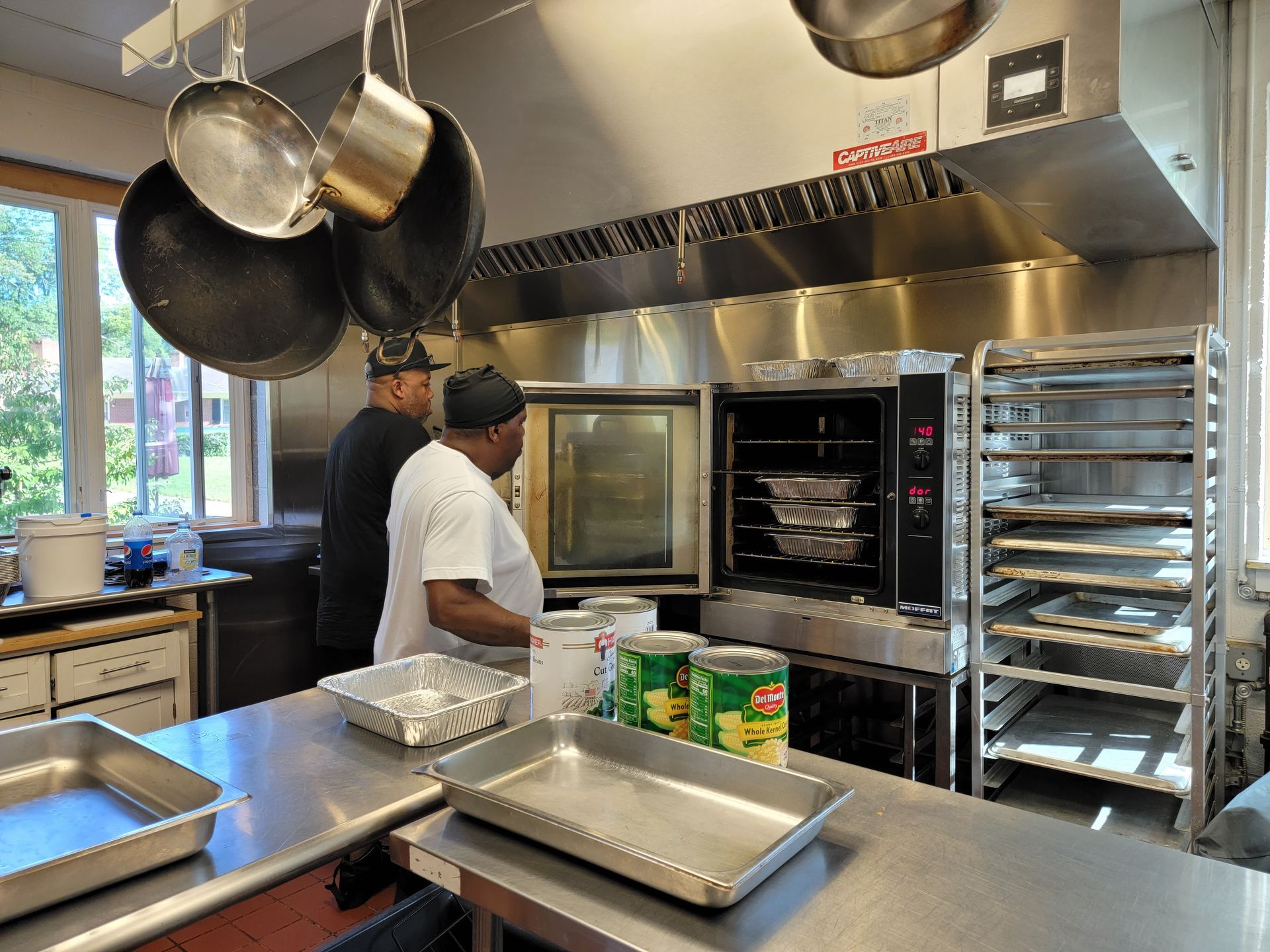 Two men are standing in a kitchen preparing food.