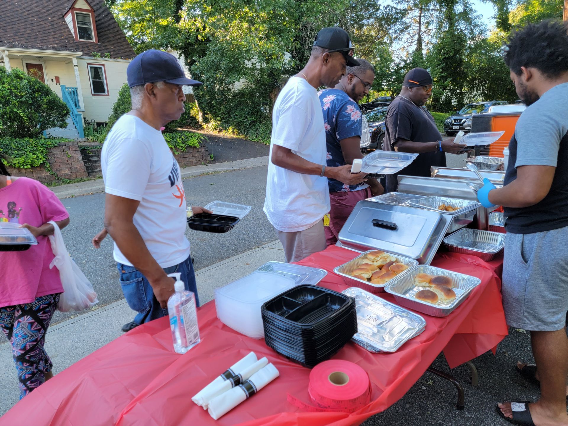 A group of people are standing around a table with food on it.
