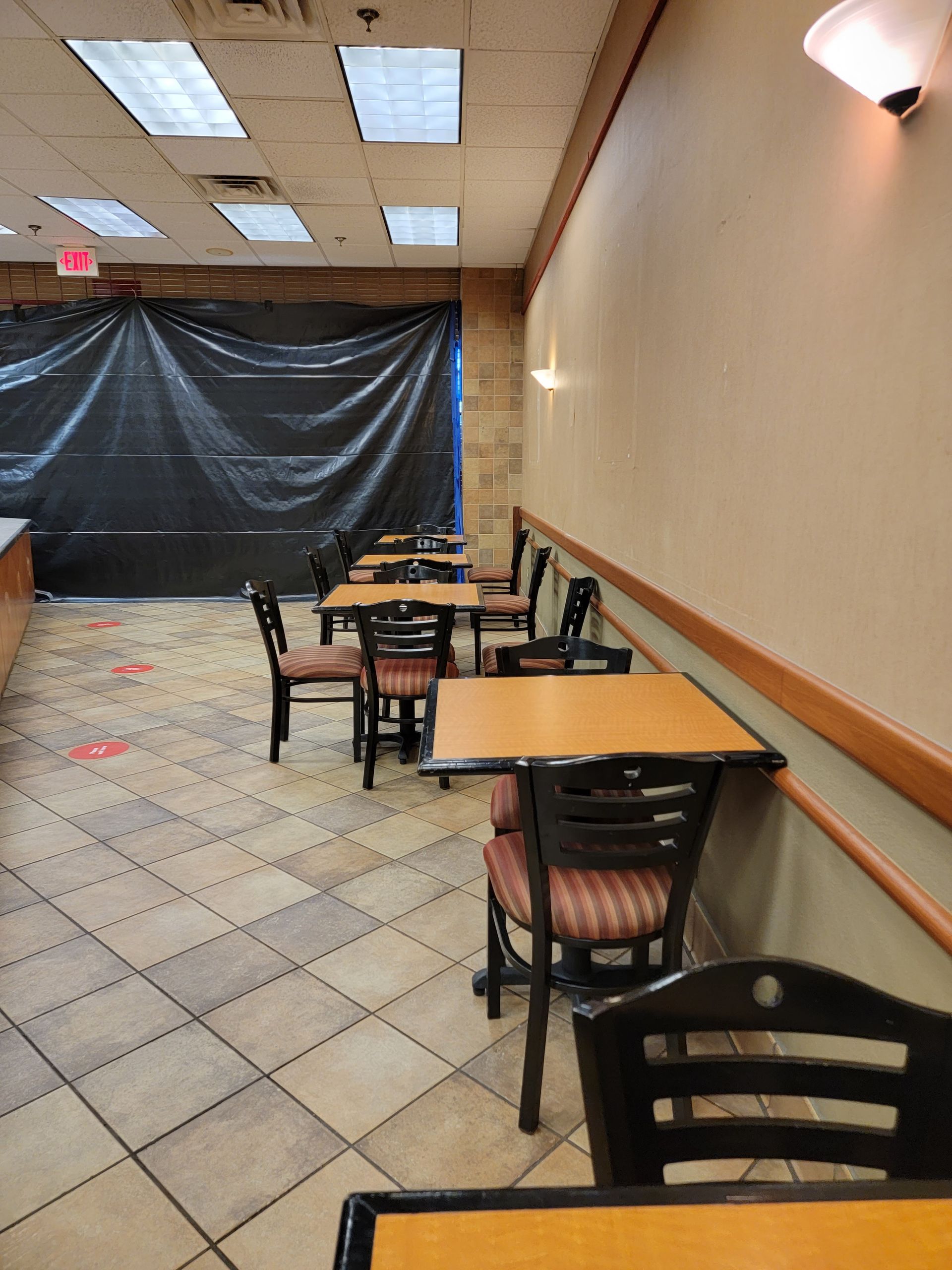 A restaurant with tables and chairs and a black tarp on the wall