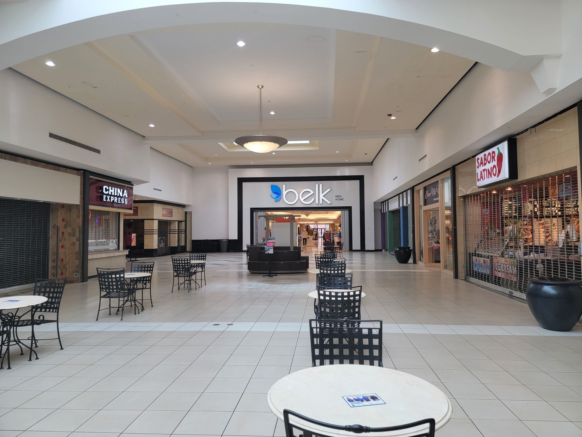 An empty mall with tables and chairs and a sign that says oak
