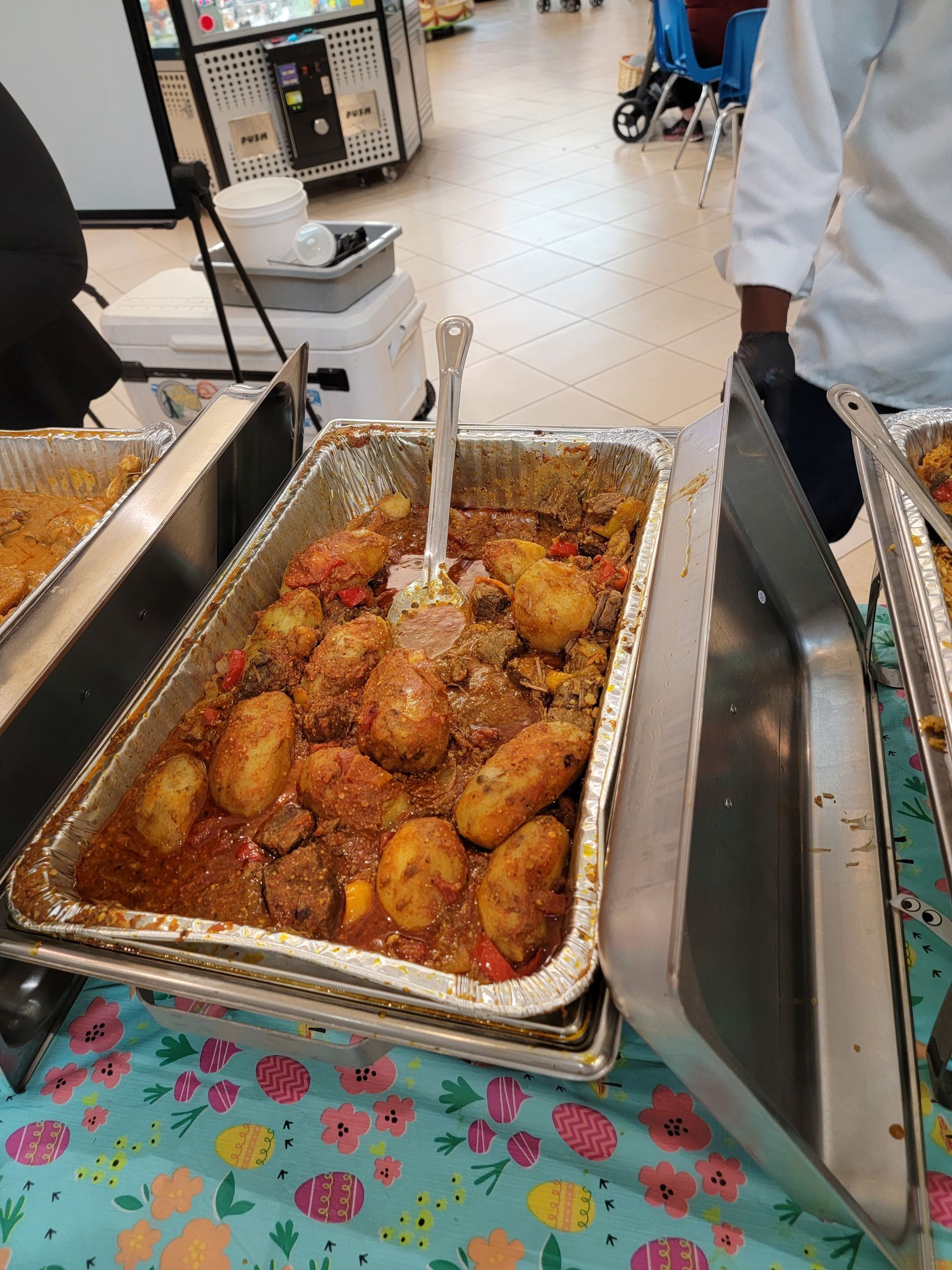 A tray of food with a spoon in it is on a table.