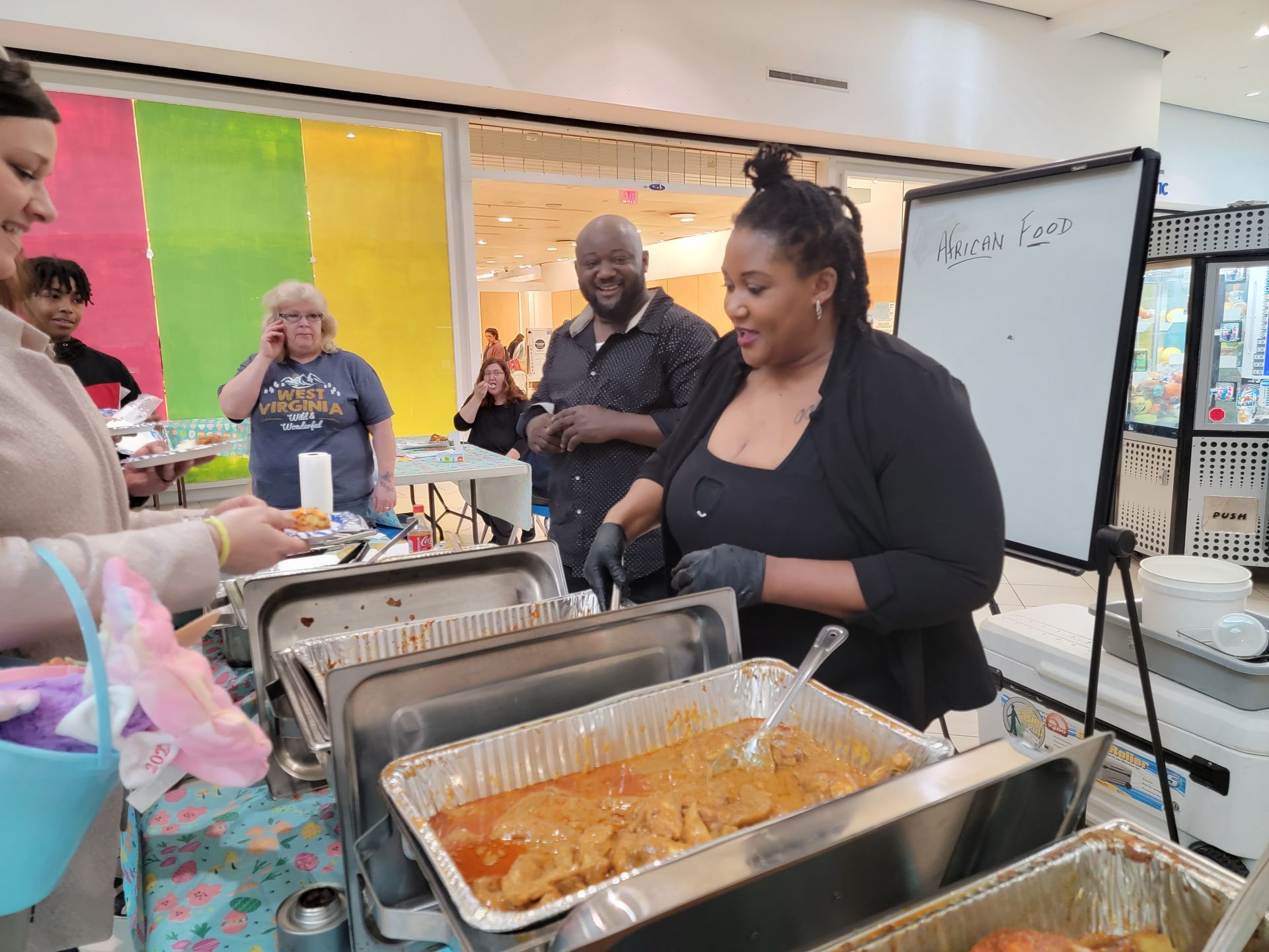 A group of people are standing around a table with trays of food.