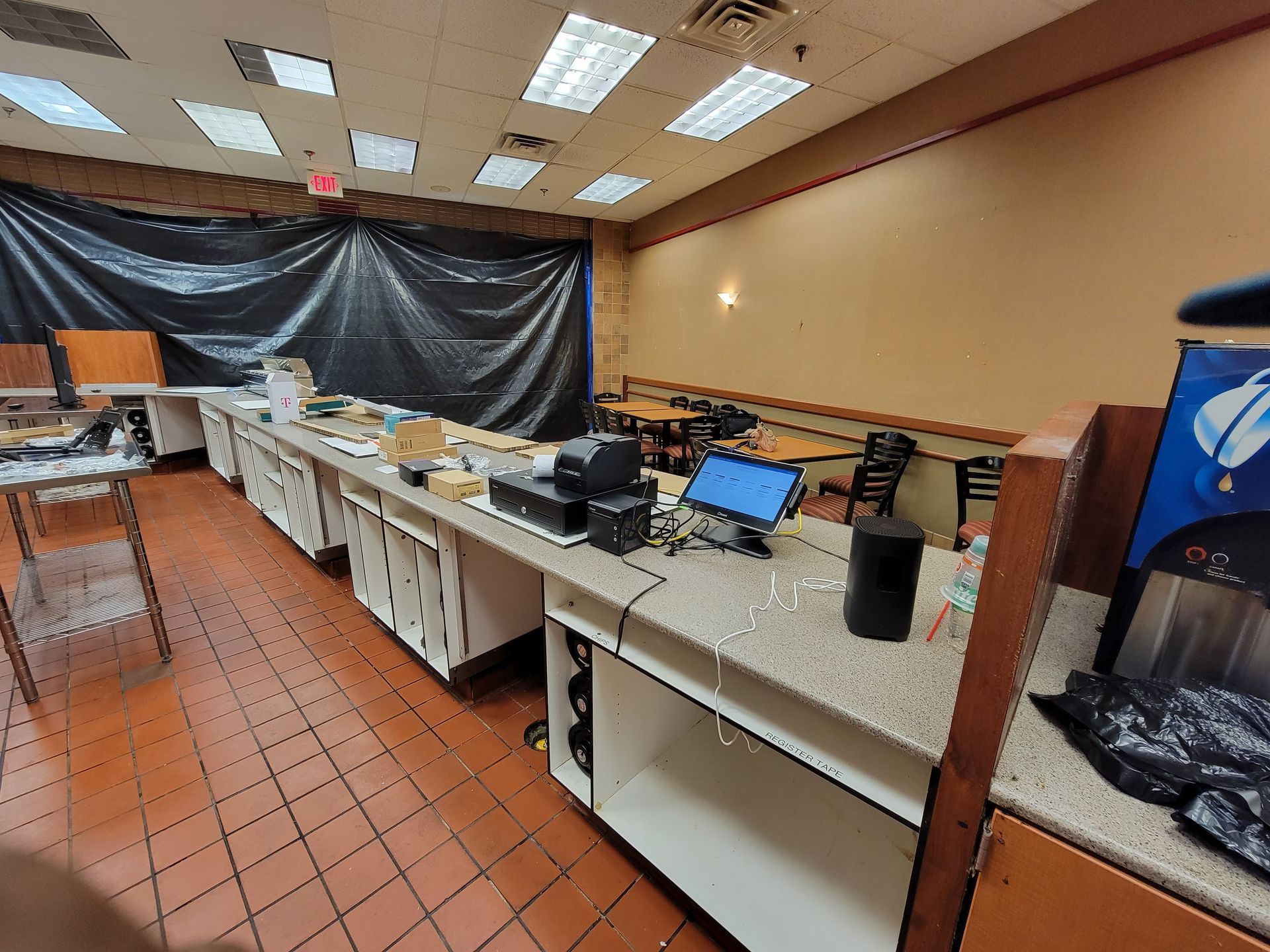 An empty restaurant with tables and counters and a vending machine.