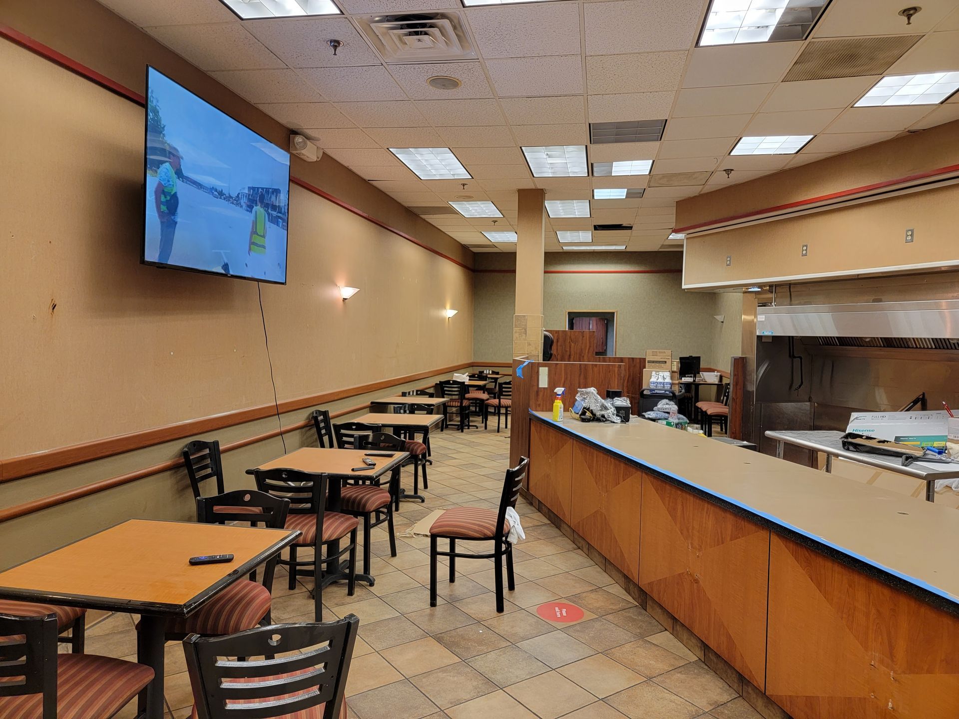 A restaurant with tables and chairs and a flat screen tv on the wall.
