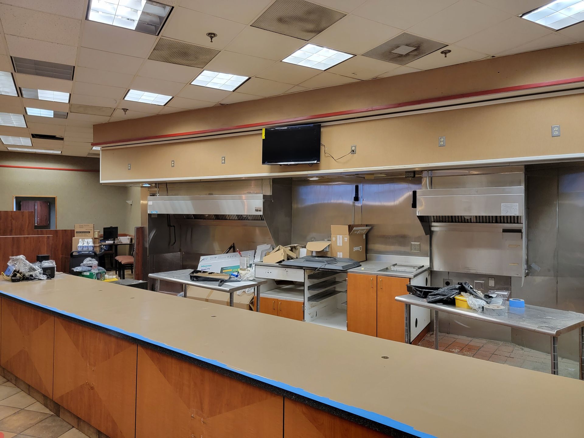 An empty restaurant kitchen with a long counter and stainless steel appliances.