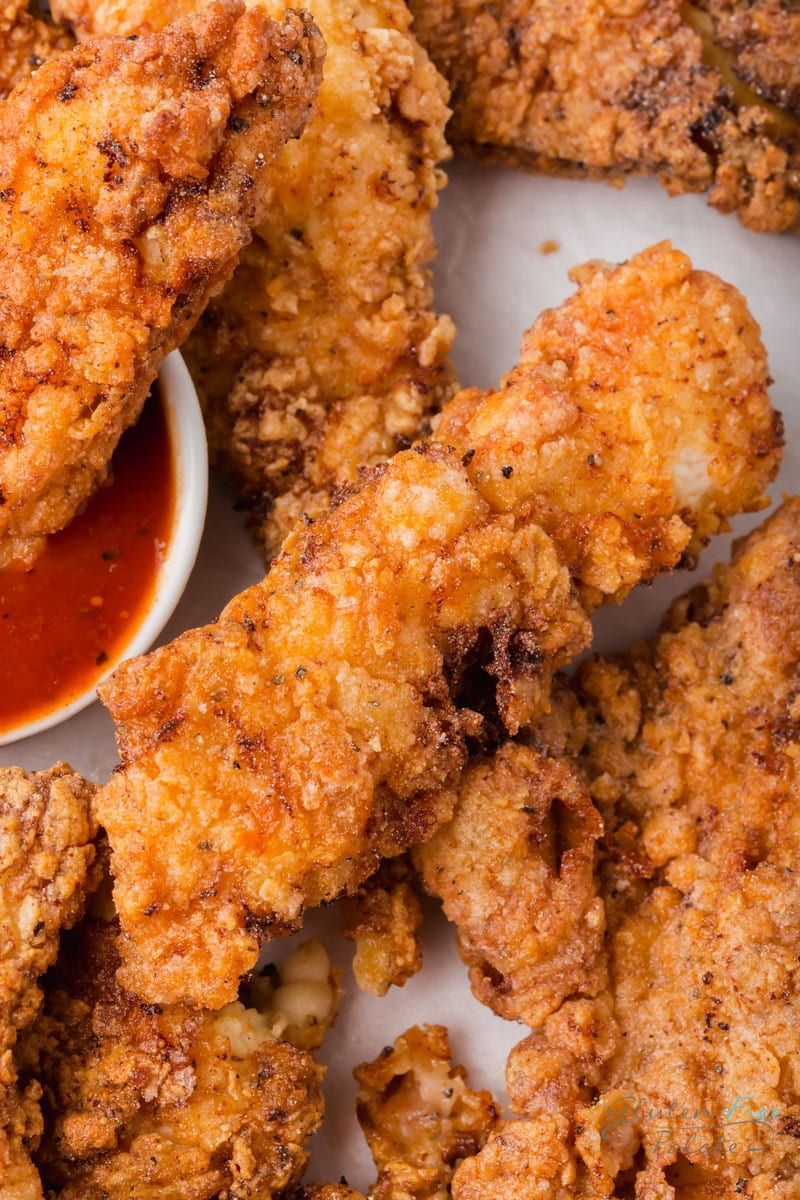 A close up of fried chicken on a plate with a dipping sauce.
