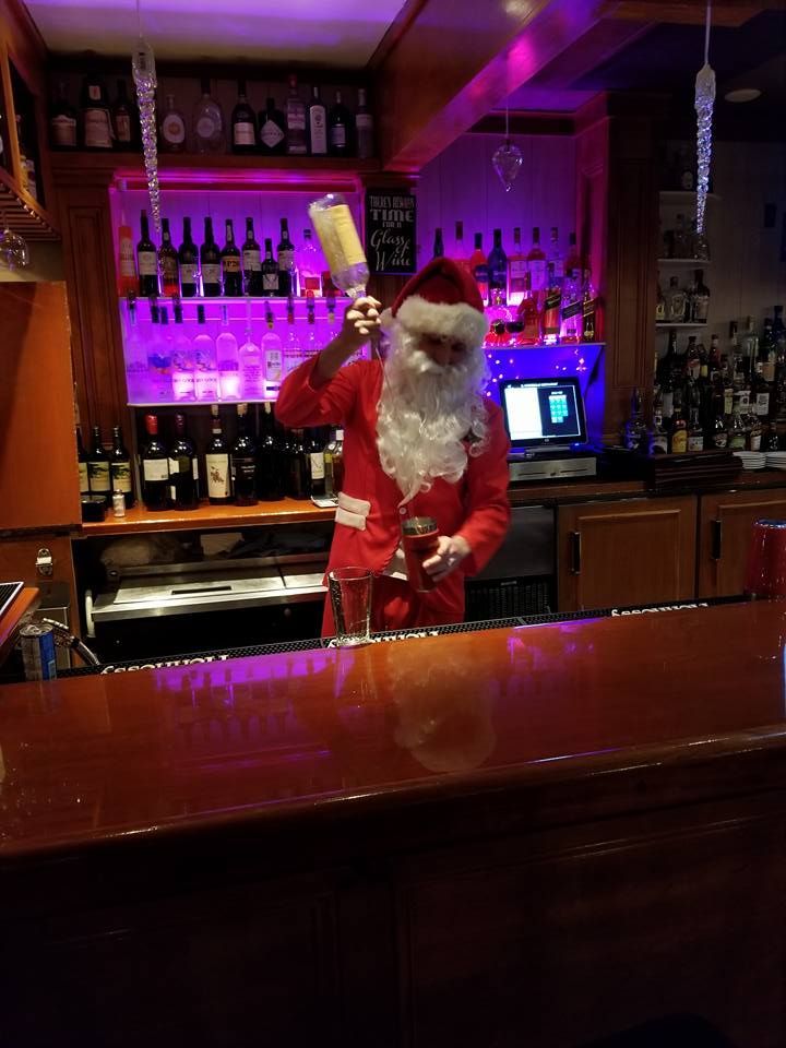 A man dressed as santa claus is standing at a bar
