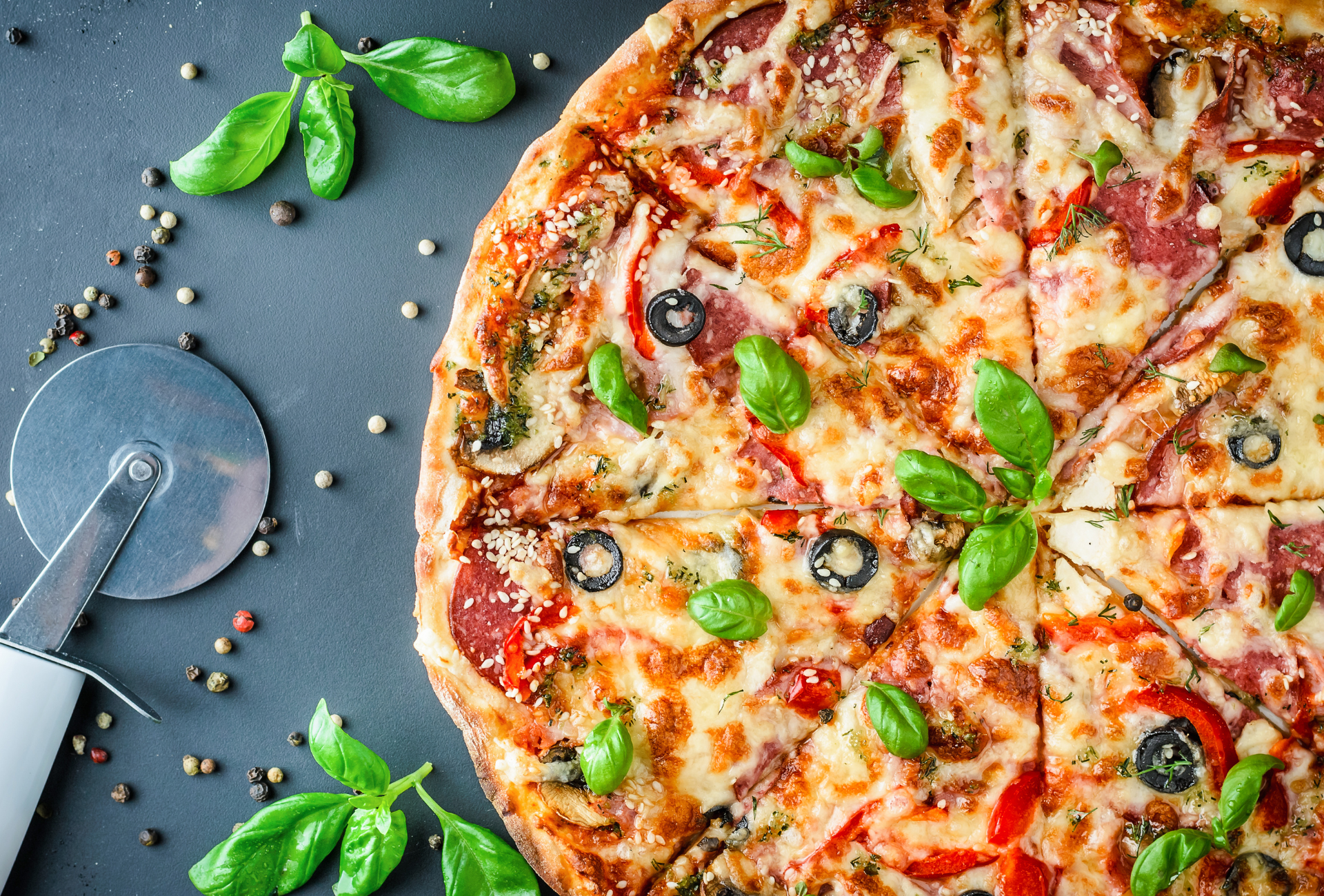 A pizza is sitting on a table next to a pizza cutter.