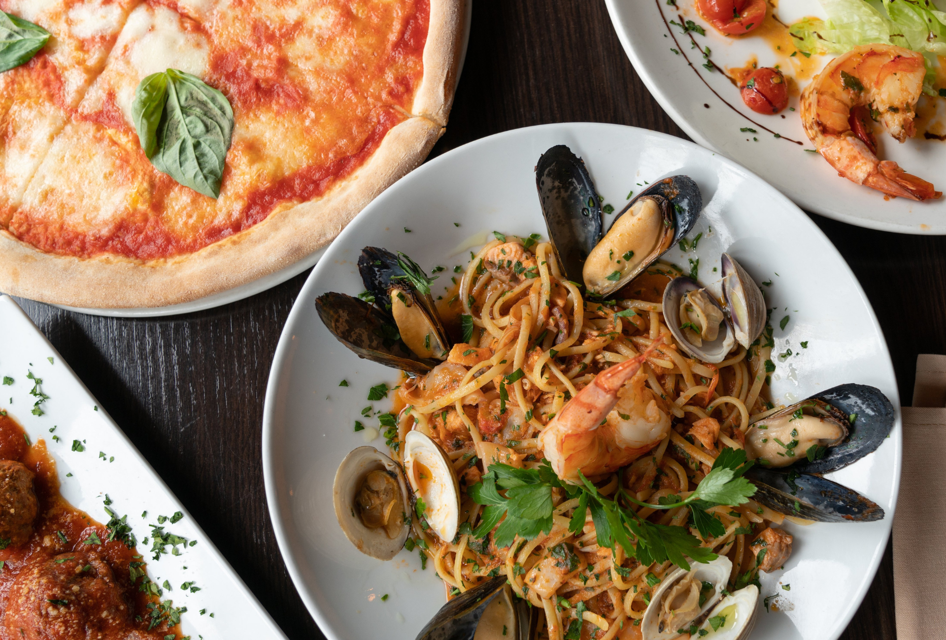 A pizza and a plate of spaghetti are on a table.