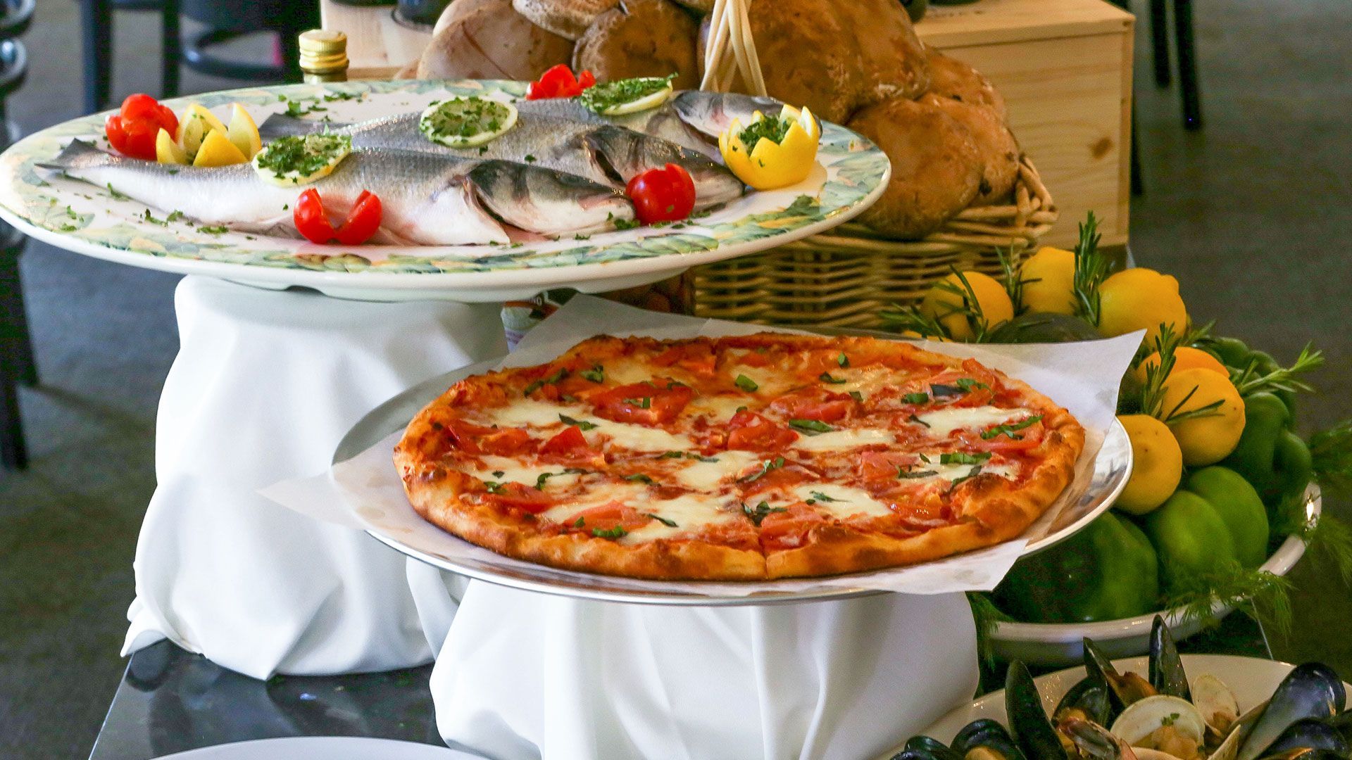 A pizza on a plate next to a plate of fish