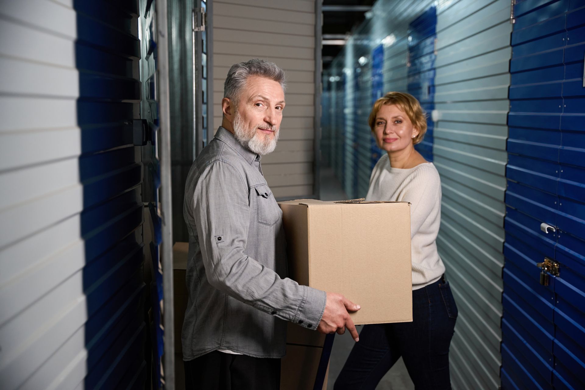 Couple moving boxes into storage while comparing storage unit prices in North Little Rock, AR.