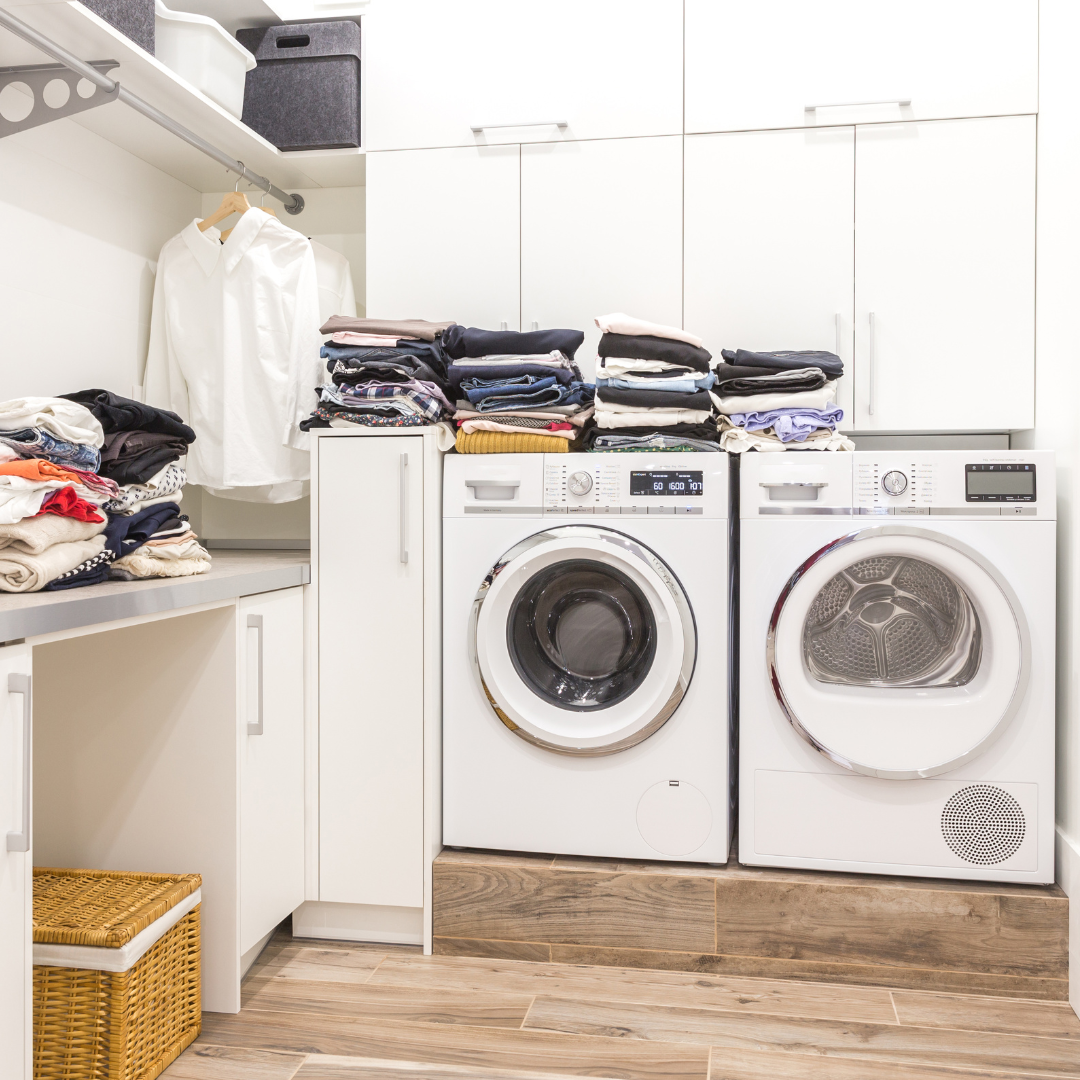 A laundry room with a washer and dryer filled with clothes.