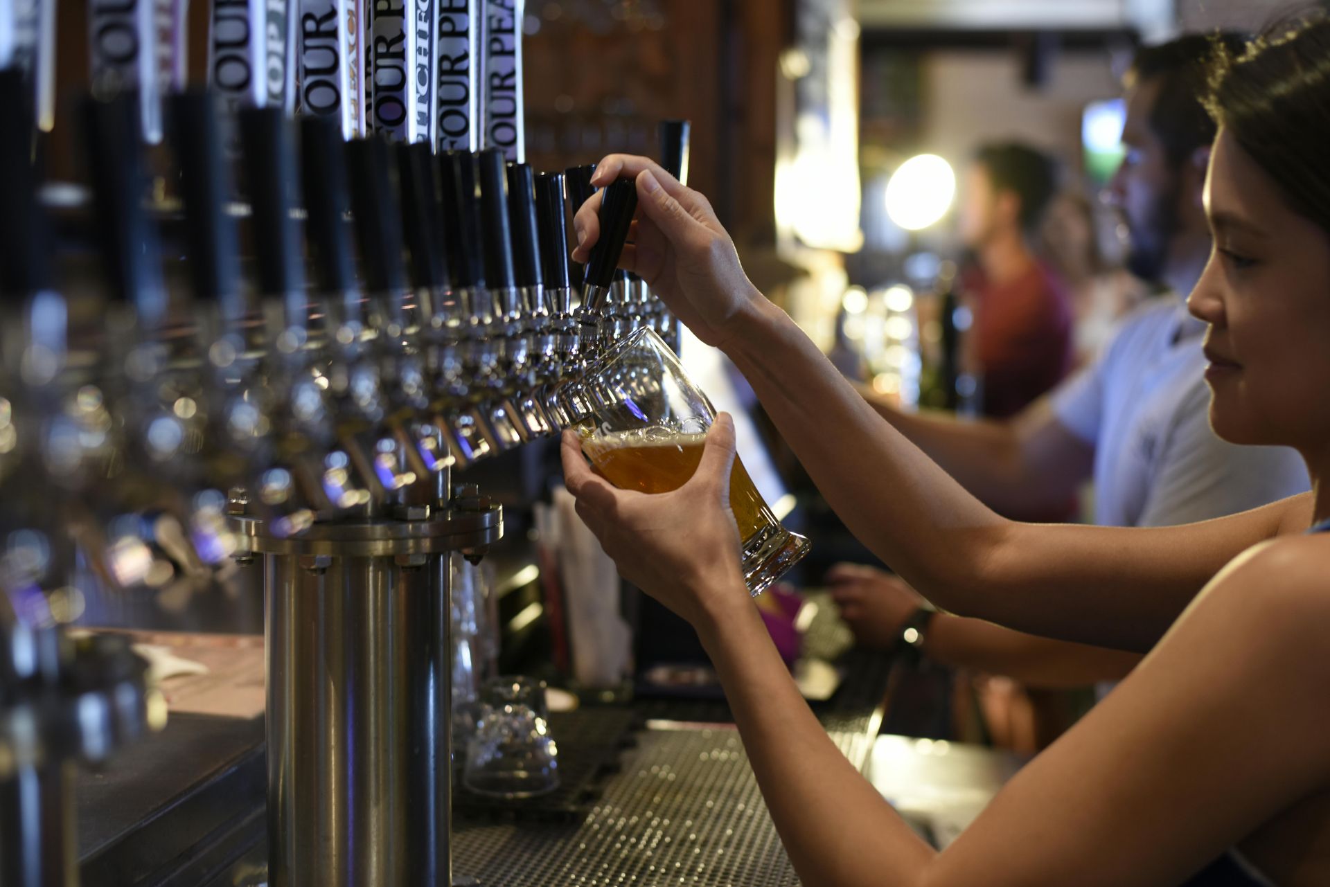 A woman is pouring beer into a glass at a bar. commercial plumbing