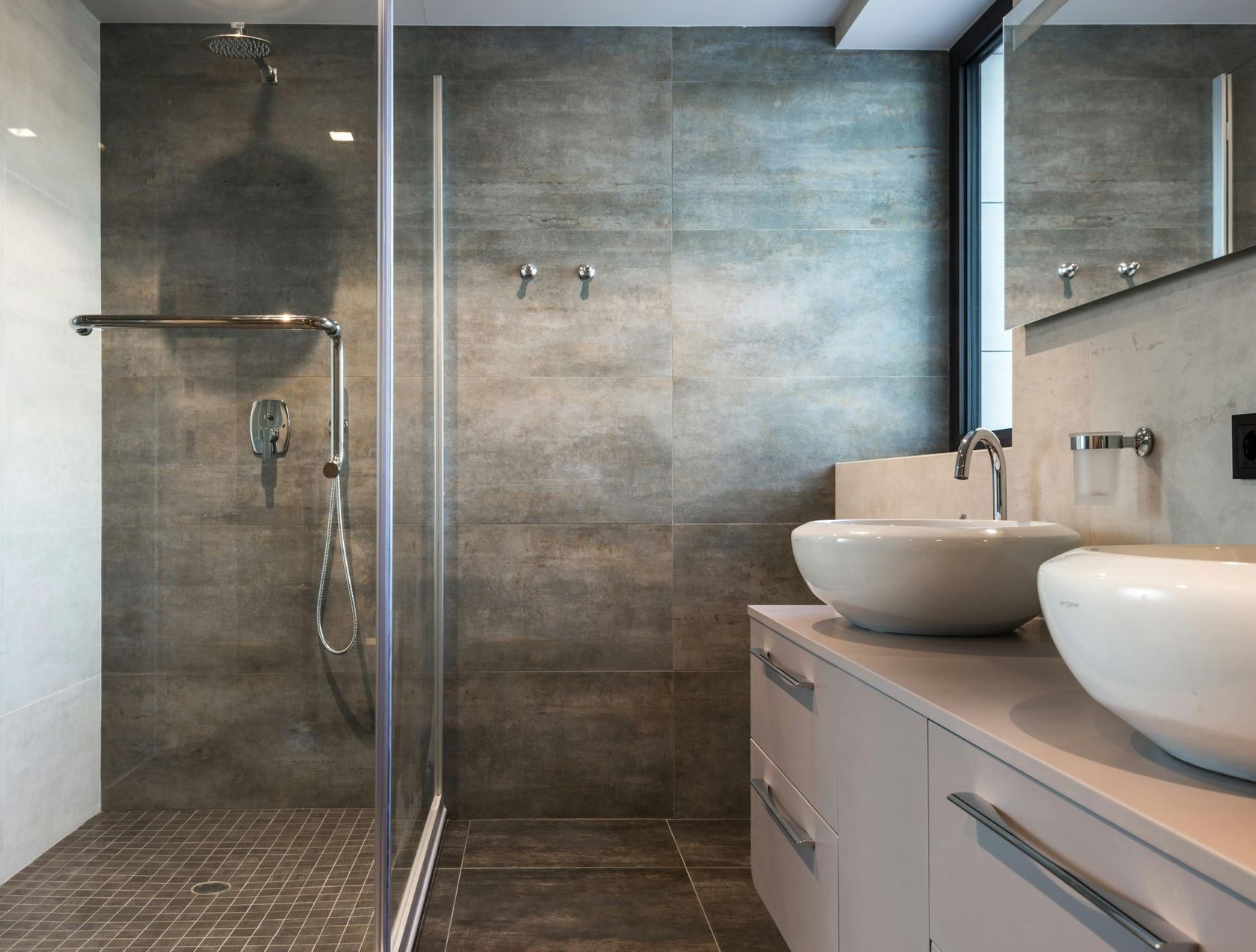 A bathroom with two sinks and a walk in shower