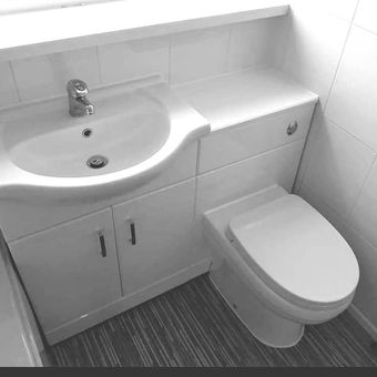 A black and white photo of a bathroom with a sink and toilet.