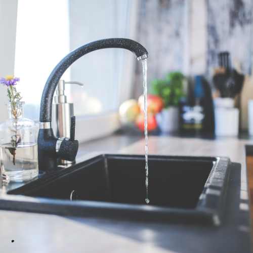 A kitchen sink with water running from the faucet
