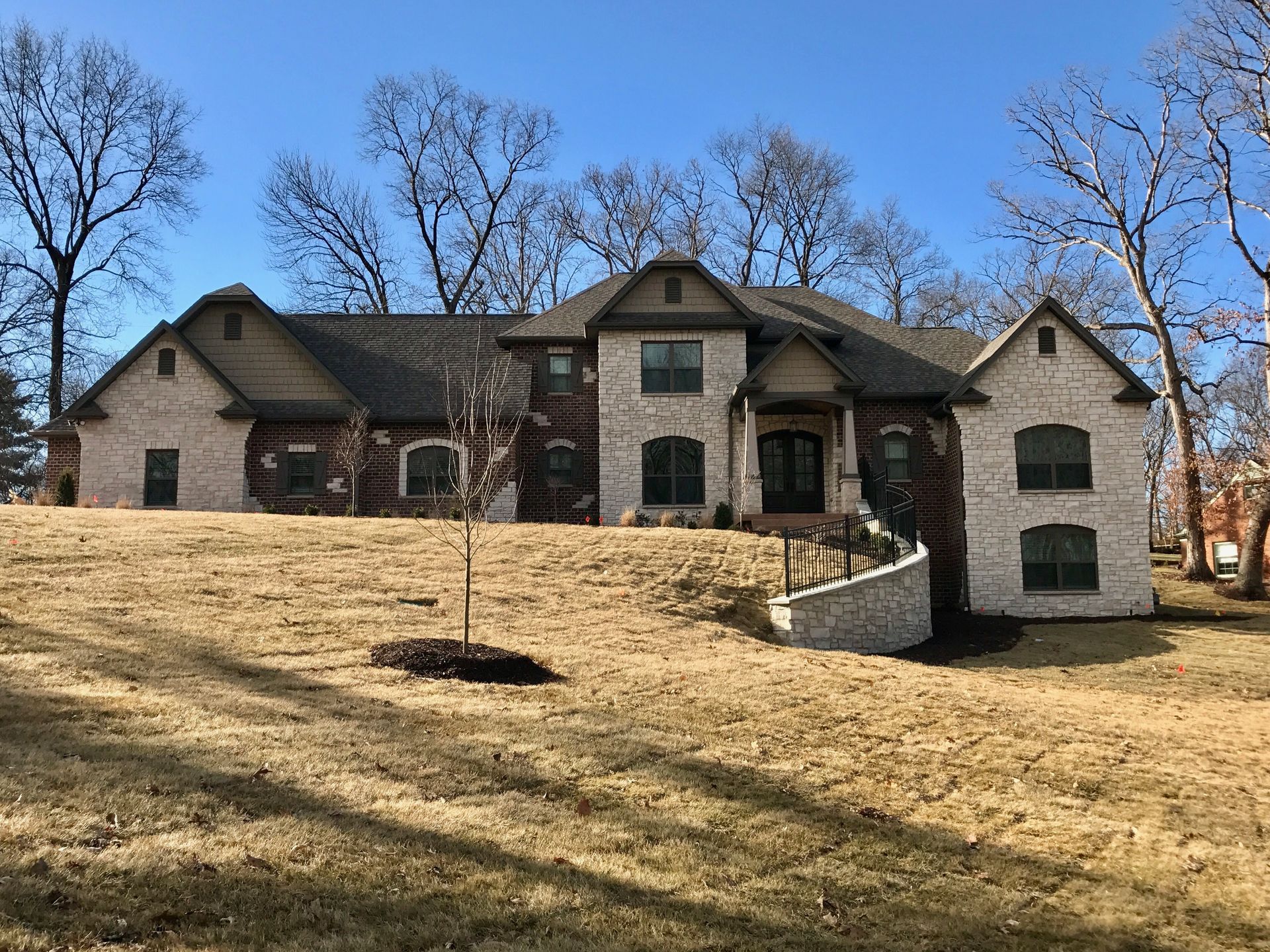 A large brick house is sitting on top of a grassy hill.