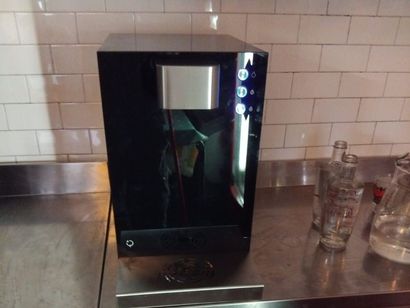 Elettrodomestico da appoggio nero su un piano cucina con frontale lucido e pannello di controllo sulla destra.