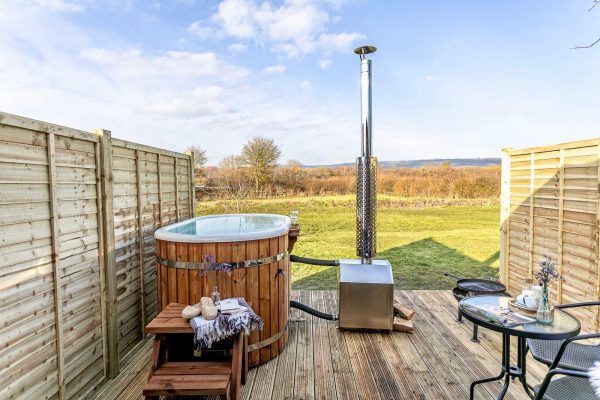 Wooden deck with hot tub, seating, and a view of open countryside