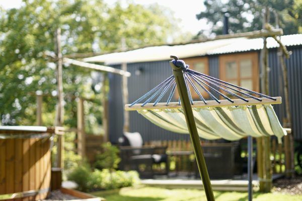 Hammock in a sunny backyard with a wooden shed and trees in the background