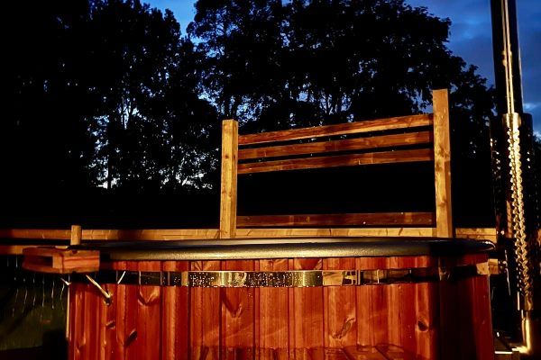 Wooden bench on a red fence at dusk, silhouetted against dark trees and a deep blue sky.