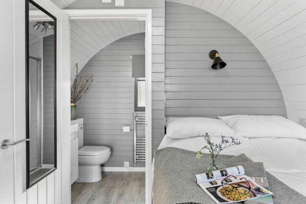 Bright gray bedroom with arched wall, small ensuite bathroom, and tray on bed with flowers and magazine