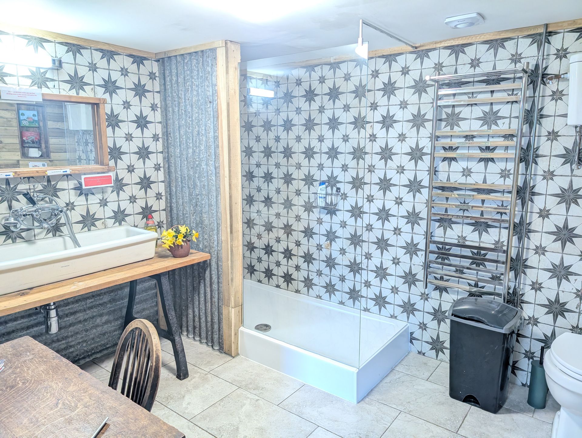 Bathroom with star-pattern wallpaper, bathtub, vanity, and gray trash bin