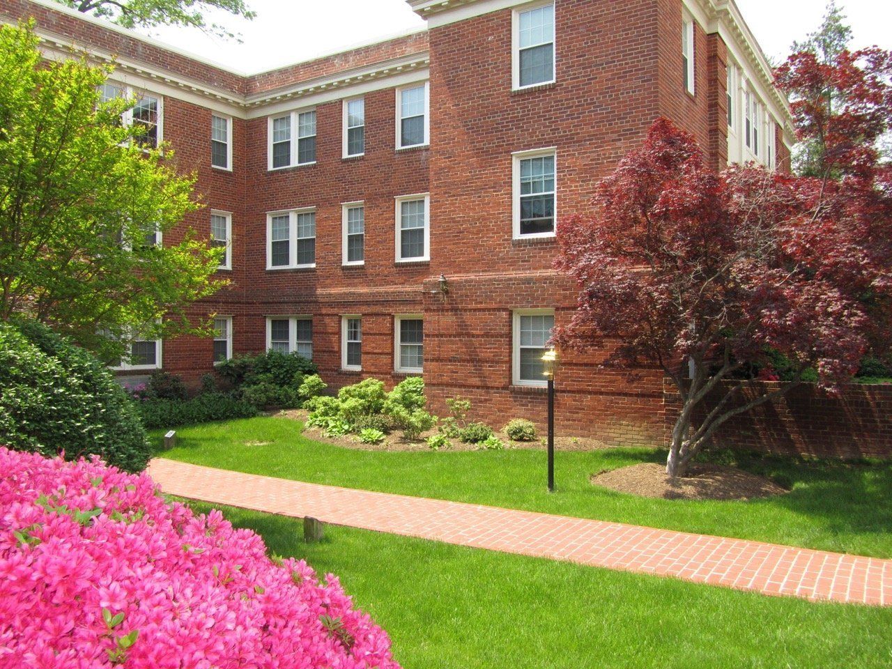 Red brick apartment courtyard path highlighting walkable communities and landscaping.