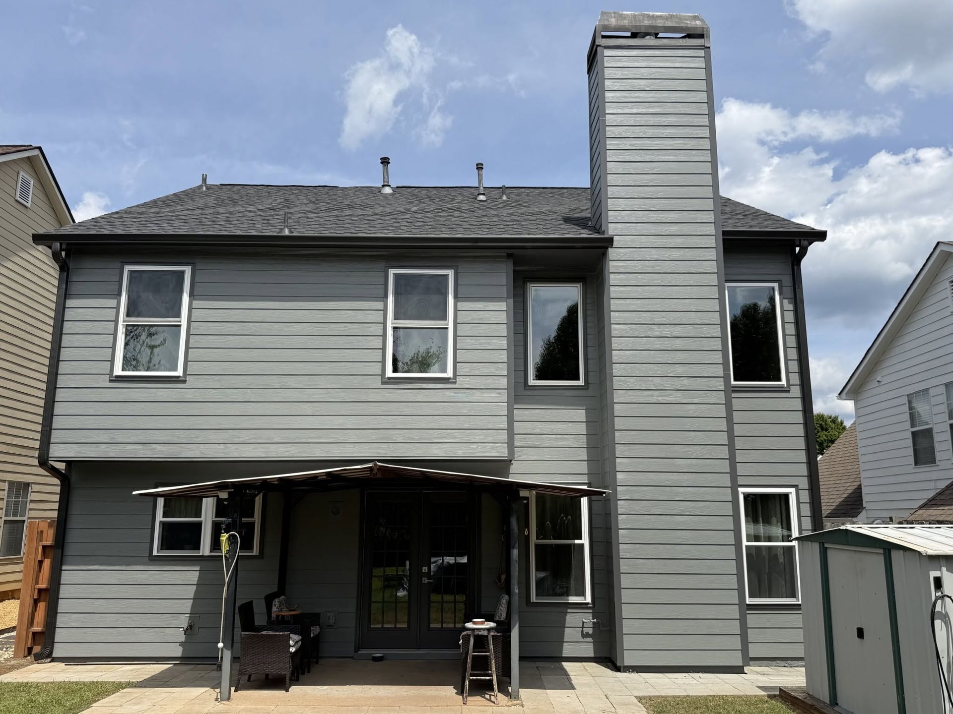 Gray two-story house with a covered patio and tall central chimney