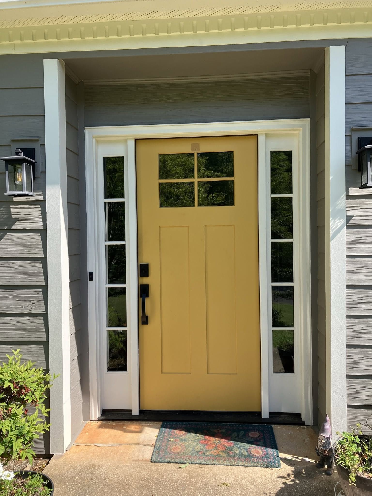 Front porch entry with a yellow front door, sidelights, and stone siding.