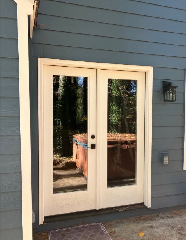 White French doors on a blue house exterior, with a hot tub visible behind the glass.