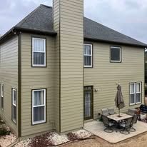 Two-story beige house with dark roof and patio table beneath an umbrella