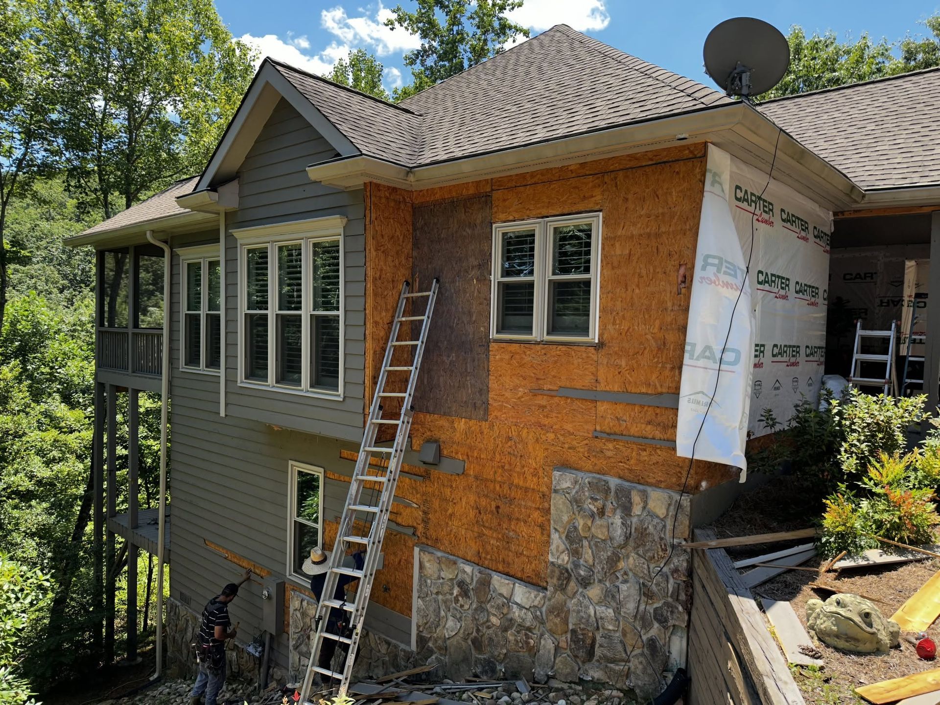 House exterior under renovation with ladder leaning against brick wall and construction wrap on one side